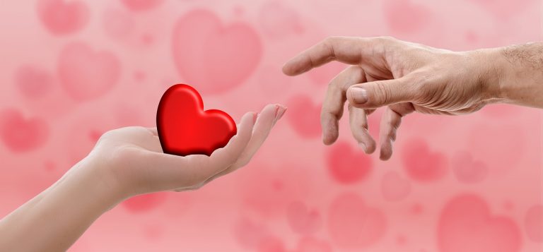 Sharing the love - woman's hand sharing a red heart