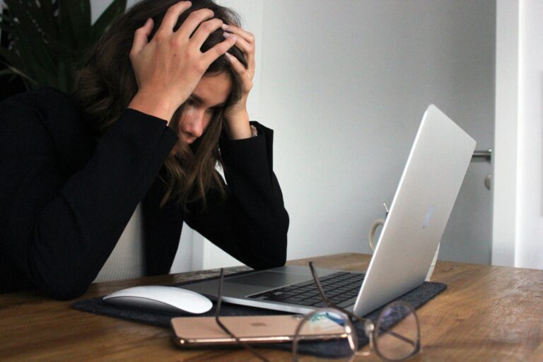 A woman sits at her desk, frustrated with a bad user experience on her computer.
