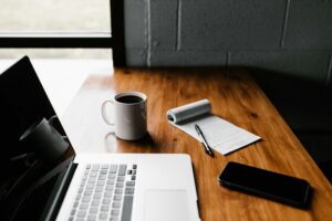 Clean workspace with laptop, notebook, coffee, and phone on a wooden desk, representing thoughtful website design and usability.