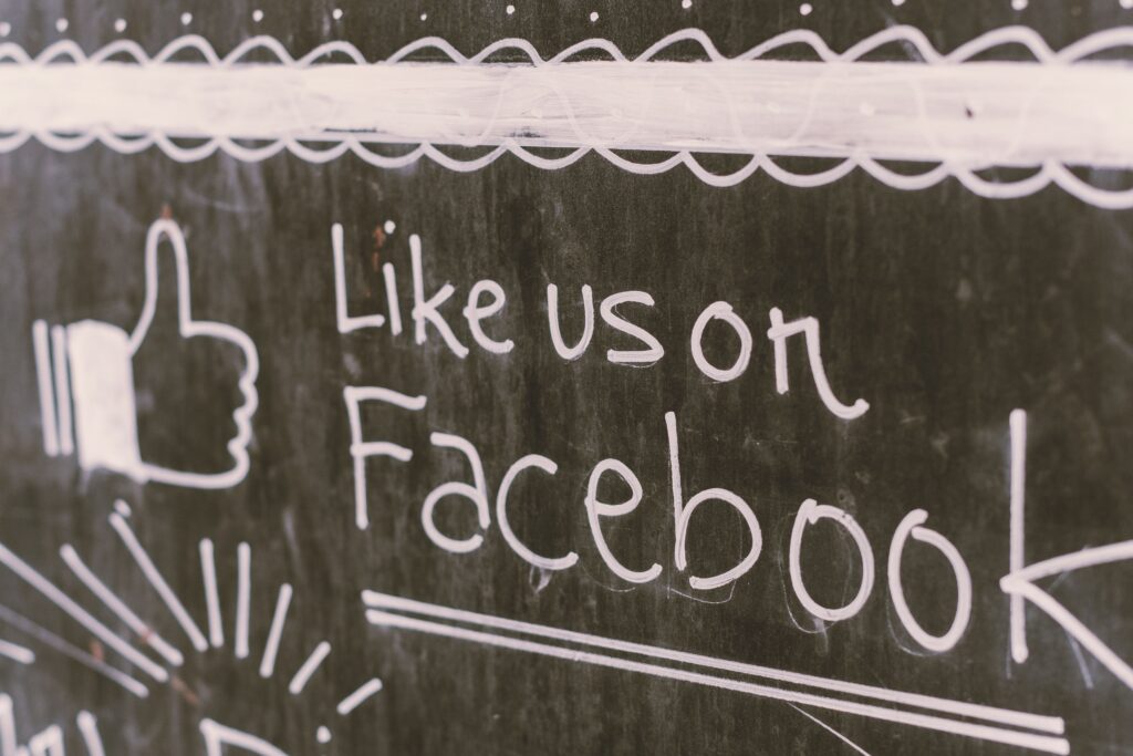 A chalkboard with "Like Us On Facebook" written on it, showing the differentiation between old-school marketing and digital advertising.