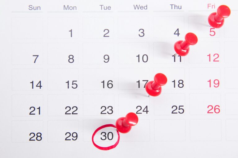 A wall calendar with red pushpins marking a trail of important dates leading to a circled date on the 30th, representing the importance of planning ahead for seasonal and holiday marketing campaigns.