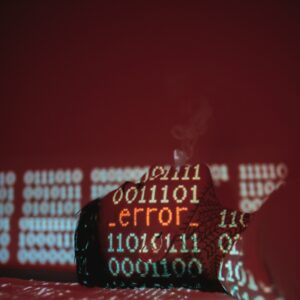 Binary code and error messages projected in red and teal onto a tattooed hand against a dark red background.