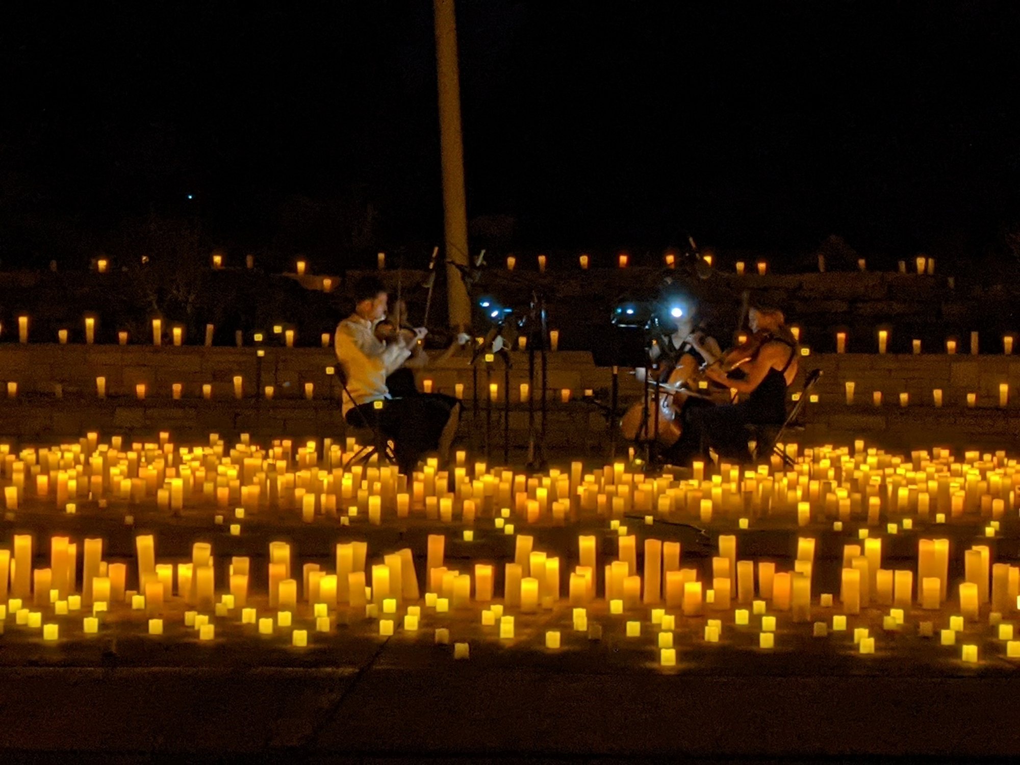 A string quartet playing at night, surrounded by hundreds of glowing candles at Belmar Park in Lakewood, Colorado