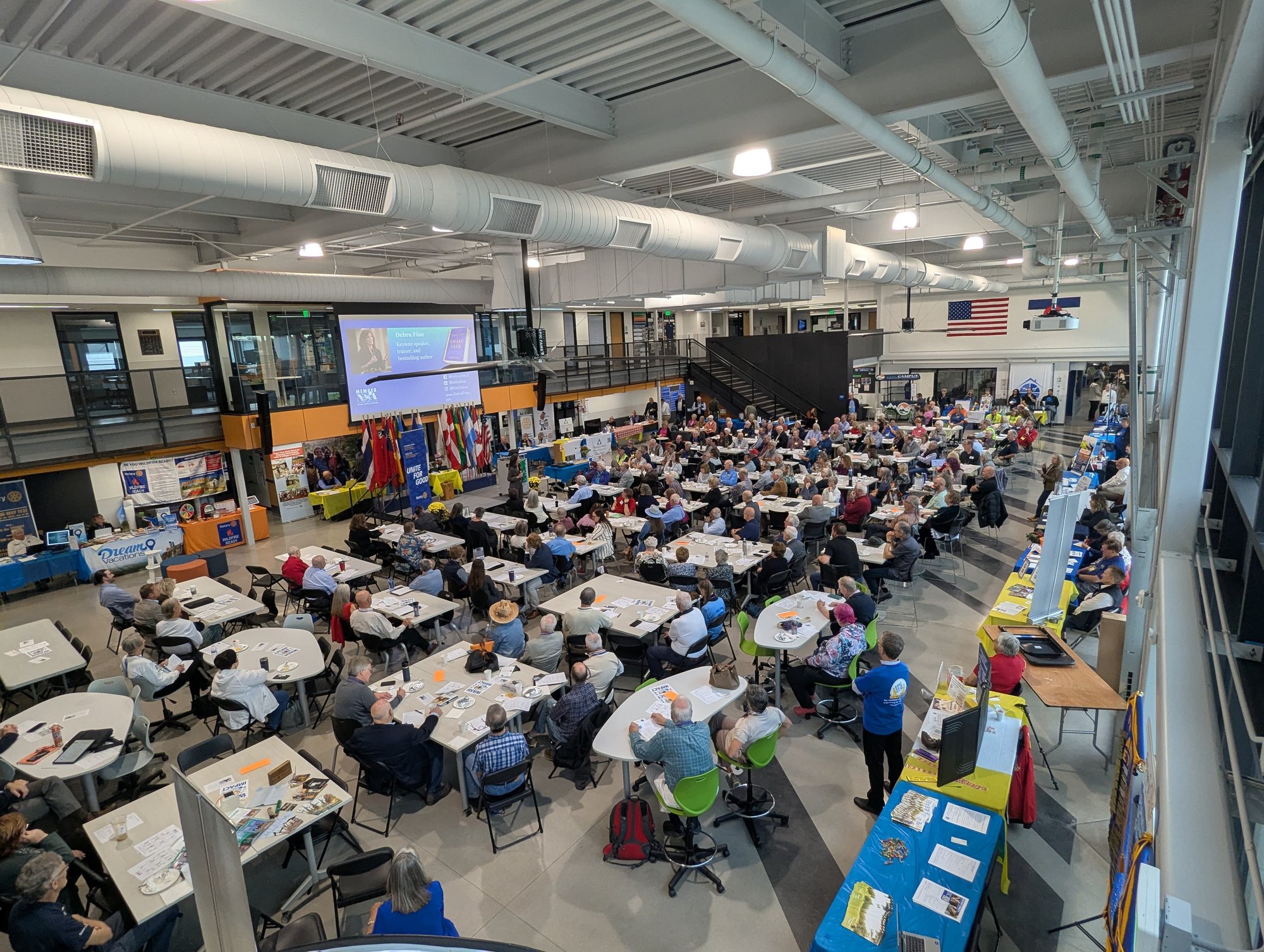 A large hall full of round tables of Rotarians facing a presentation screen