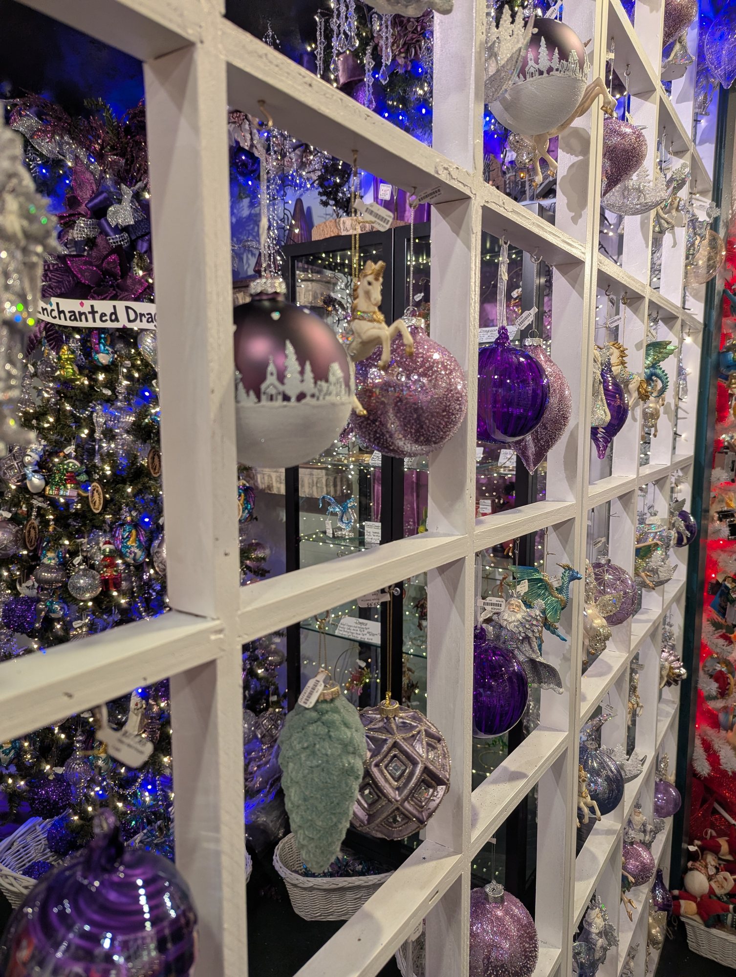 A wall of white shelves filled with purple and silver Christmas ornaments
