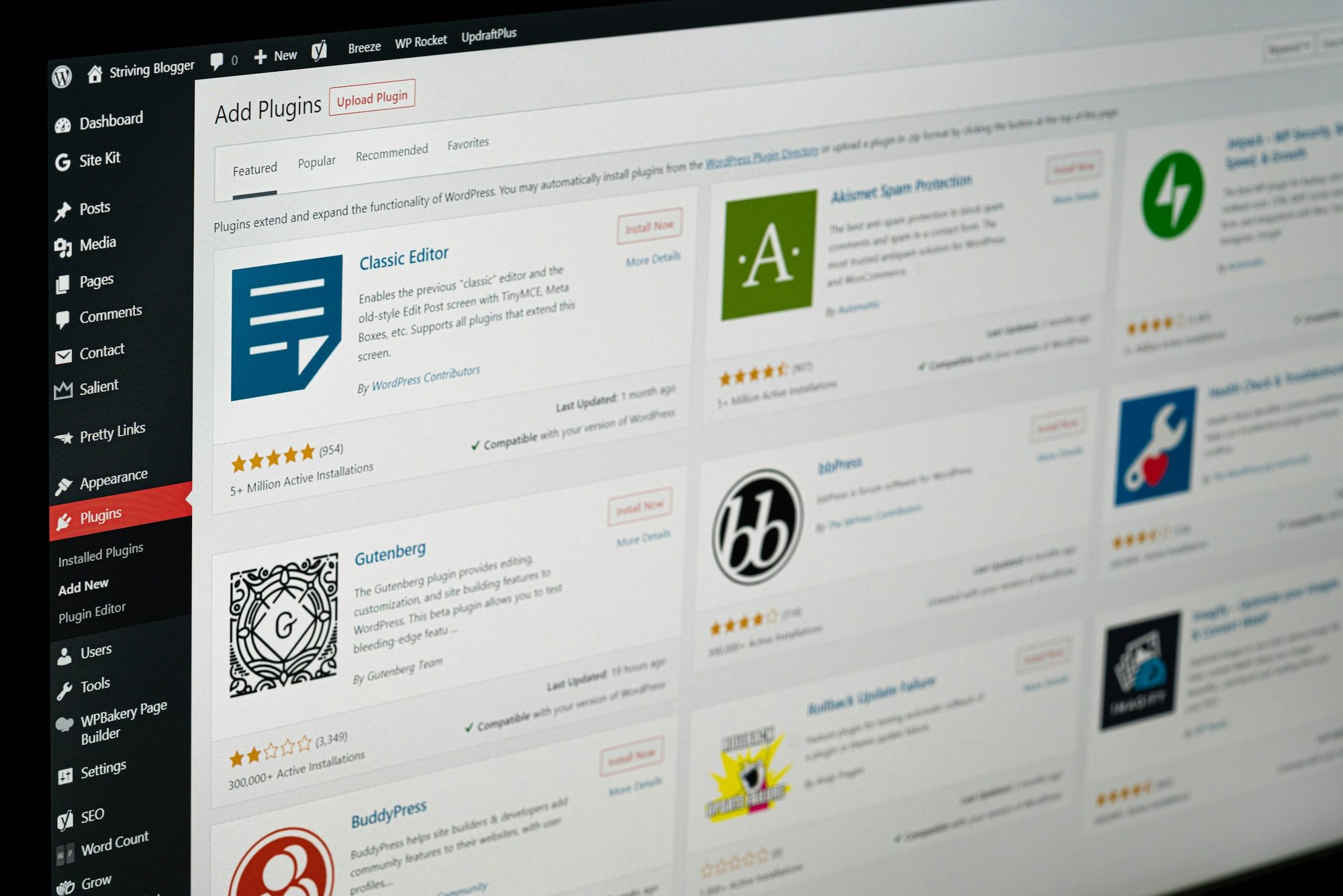 A computer screen showing the WordPress admin Add Plugins page, with plugin cards for Classic Editor, Akismet, Gutenberg and bbPress beside the dark admin menu